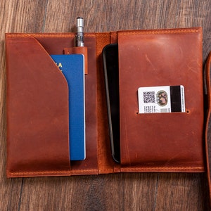 May include: A brown leather travel wallet with a passport, phone, and card holder. The wallet has a strap for carrying.