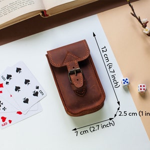 May include: A brown leather pouch with a buckle closure. The pouch measures 4.7 inches tall, 2.7 inches wide, and 1 inch deep.