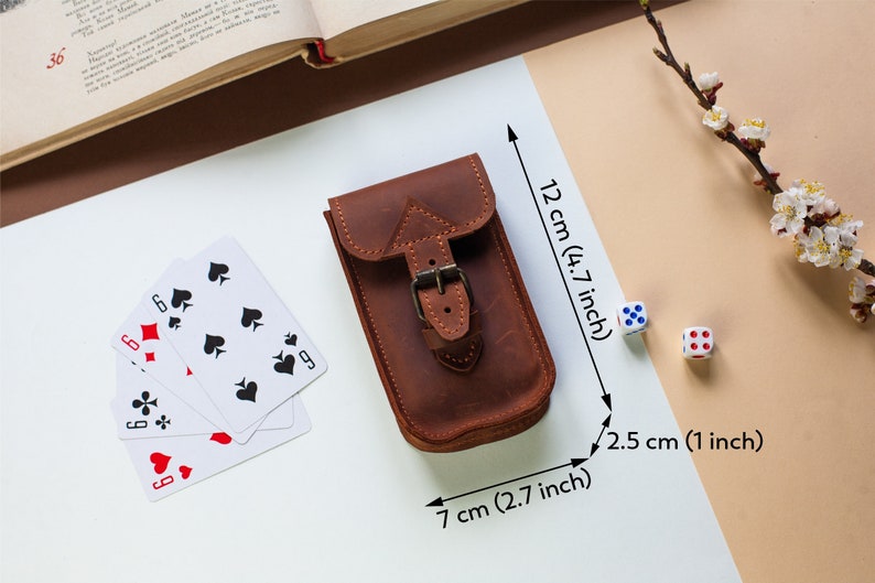 May include: A brown leather pouch with a buckle closure. The pouch measures 4.7 inches tall, 2.7 inches wide, and 1 inch deep.