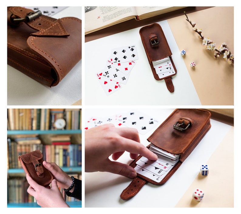 May include: A brown leather case with a buckle closure, designed to hold a deck of cards. The case is open, revealing a deck of playing cards inside. The case is on a light brown surface with a few playing cards scattered around it.