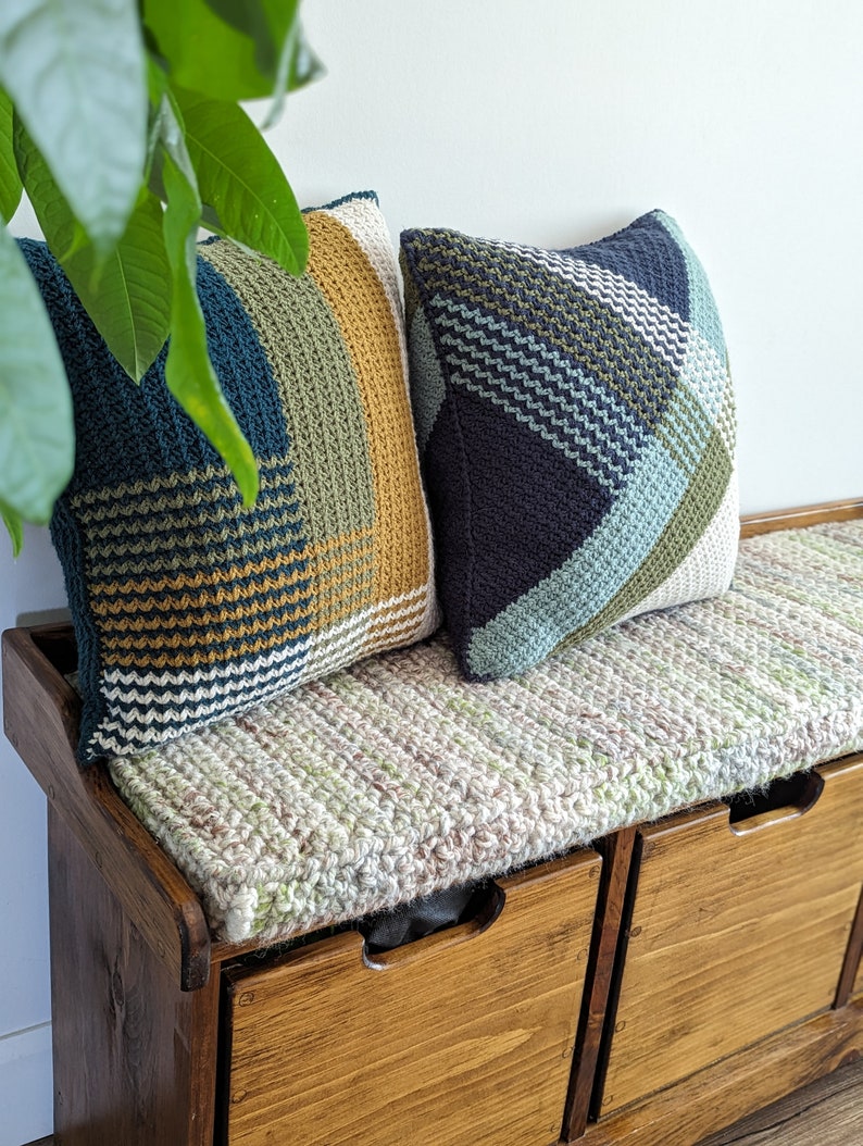 Two geometric striped crochet pillows on a wooden bench