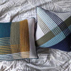 Two geometric striped crochet pillows on a grey bedspread
