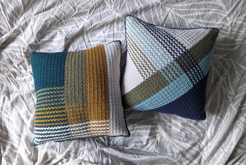 Two geometric striped crochet pillows on a grey bedspread