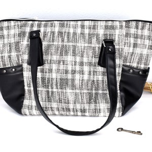 May include: A black and white checked tote bag with black leather accents and a zip closure. The bag has two top handles and a detachable shoulder strap.