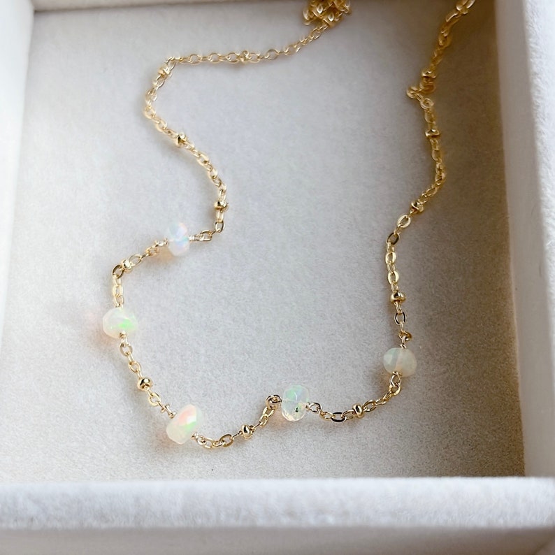 A delicate gold chain necklace with small white opal beads.