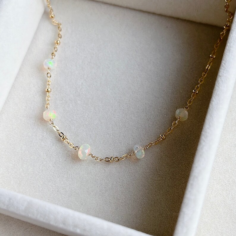 May include: A delicate gold chain necklace with five small white opal stones.