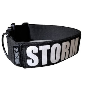 Peut inclure: Collier de chien noir avec un patch réfléchissant blanc qui dit "STORM" et le texte "SPECDOGS" sur le côté.