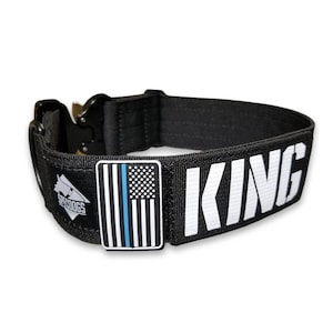 May include: Black dog collar with a white "KING" text and a blue line American flag patch. The collar has a black buckle and a black and white logo that says "SPODOGS".