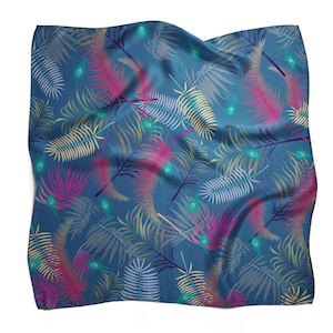 Pode incluir: Um lenço de seda azul com um padrão de folhas tropicais. As folhas são em tons de rosa, verde e amarelo. Há também pequenas penas de pavão espalhadas por todo o design.