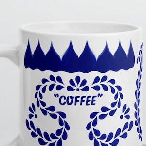 May include: White ceramic mug with a blue and white floral design. The mug has the word "COFFEE" written in blue on the front.