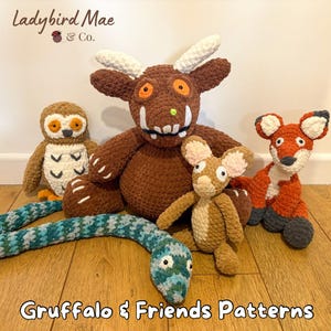 Peut inclure: Ensemble de peluches crochetées représentant les personnages du livre pour enfants "Le Gruffalo" et sa suite. Comprend un Gruffalo marron, un hibou, un renard, une souris et un serpent. Les jouets sont disposés sur une surface en bois. Le texte "Gruffalo & Friends Patterns" est en bas.