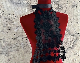 May include: A black lace collar with a satin ribbon tie. The collar is on a red mannequin and is displayed against a vintage world map.