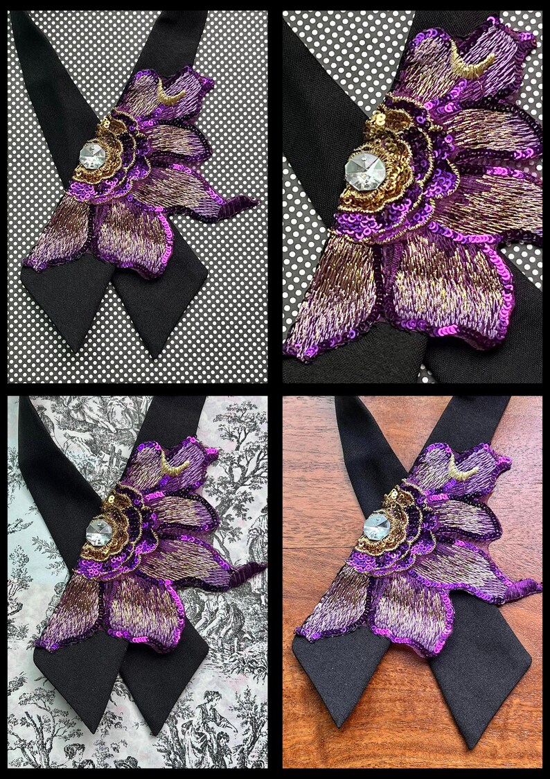 Puede incluir: Primer plano de una pajarita decorativa con una gran flor morada bordada, detalles dorados y un cristal central. La pajarita tiene una base negra y se muestra sobre varios fondos estampados.