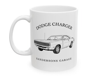May include: White ceramic mug featuring a black line drawing of a Dodge Charger. The text "Dodge Charger" is above the car image, and "Sandersons Garage" is below. The mug has a curved handle.
