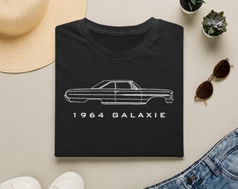 May include: A black short-sleeved t-shirt featuring a white line art illustration of a 1964 Galaxie car profile. The text 1964 GALAXIE is printed in white capital letters directly below the car graphic on the center of the chest area.
