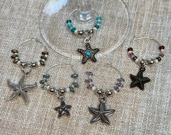 May include: Set of six silver-tone glass charms with starfish pendants. Each charm features a different color of beads, including turquoise, purple, brown, and white.