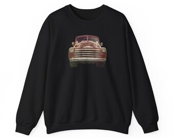 May include: Black sweatshirt featuring a vintage red pickup truck graphic. The truck is depicted head-on, showcasing its grill, headlights, and hood. The design has a slightly faded, artistic style, giving it a retro feel. The sweatshirt is a classic crew neck style.