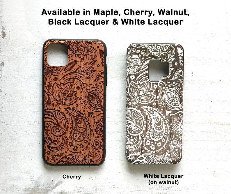 May include: Two phone cases with a paisley design. The case on the left is cherry wood with a brown paisley design. The case on the right is walnut wood with a white paisley design. The text below the cases reads "Cherry" and "White Lacquer (on walnut)".
