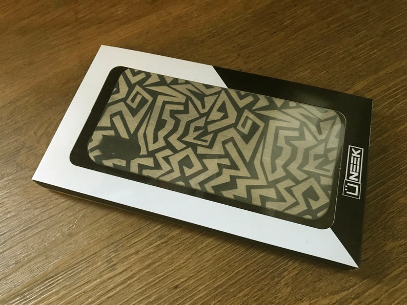 May include: A white and black phone case with a geometric pattern. The case is in a white box with a black border and the word "U'NEEK" printed on the side.