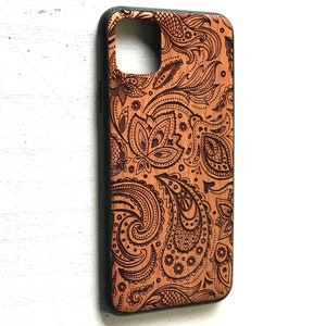May include: A brown wooden phone case with a black border and a paisley pattern.