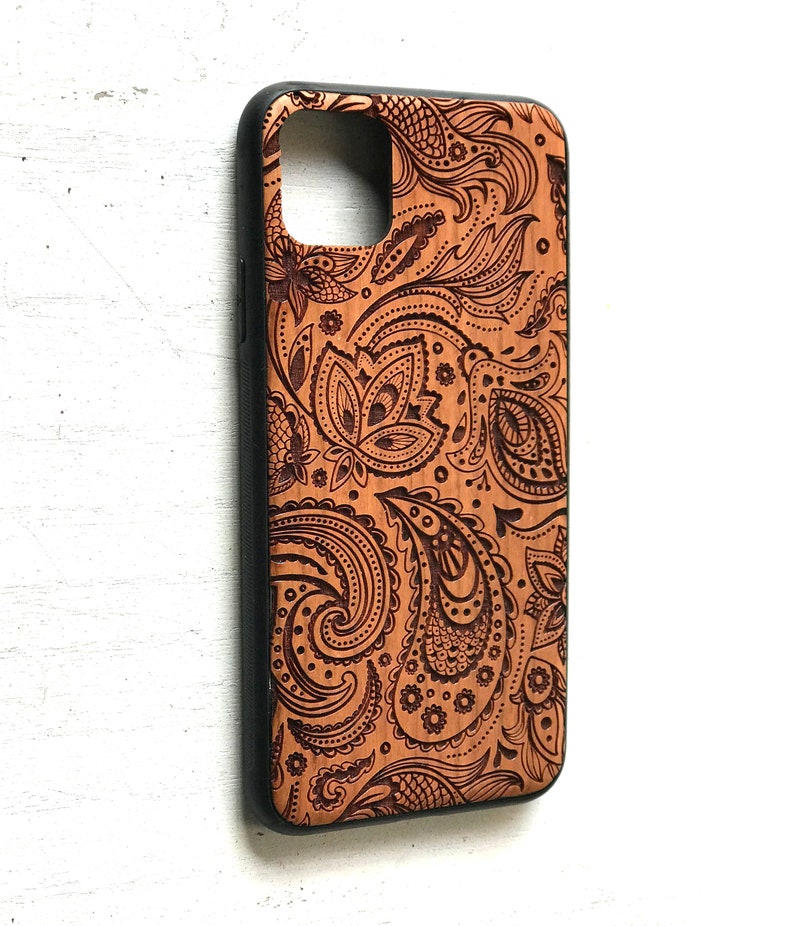 May include: A brown wooden phone case with a black border and a paisley pattern.