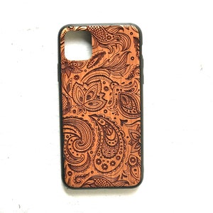 May include: A brown wooden phone case with a black border and a paisley pattern.
