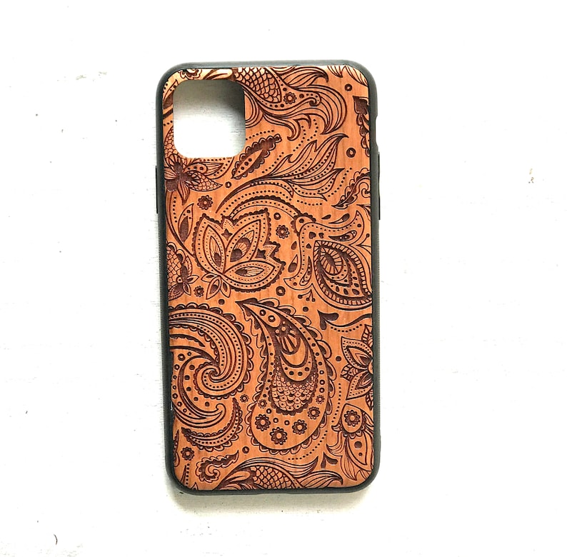 May include: A brown wooden phone case with a black border and a paisley pattern.
