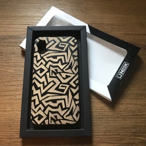 May include: A black and beige wood phone case with a geometric pattern. The case is in a black box with the word "LINEK" printed on the box.