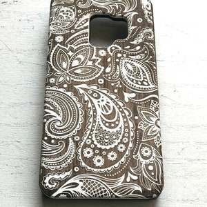 May include: A brown phone case with a white paisley pattern.