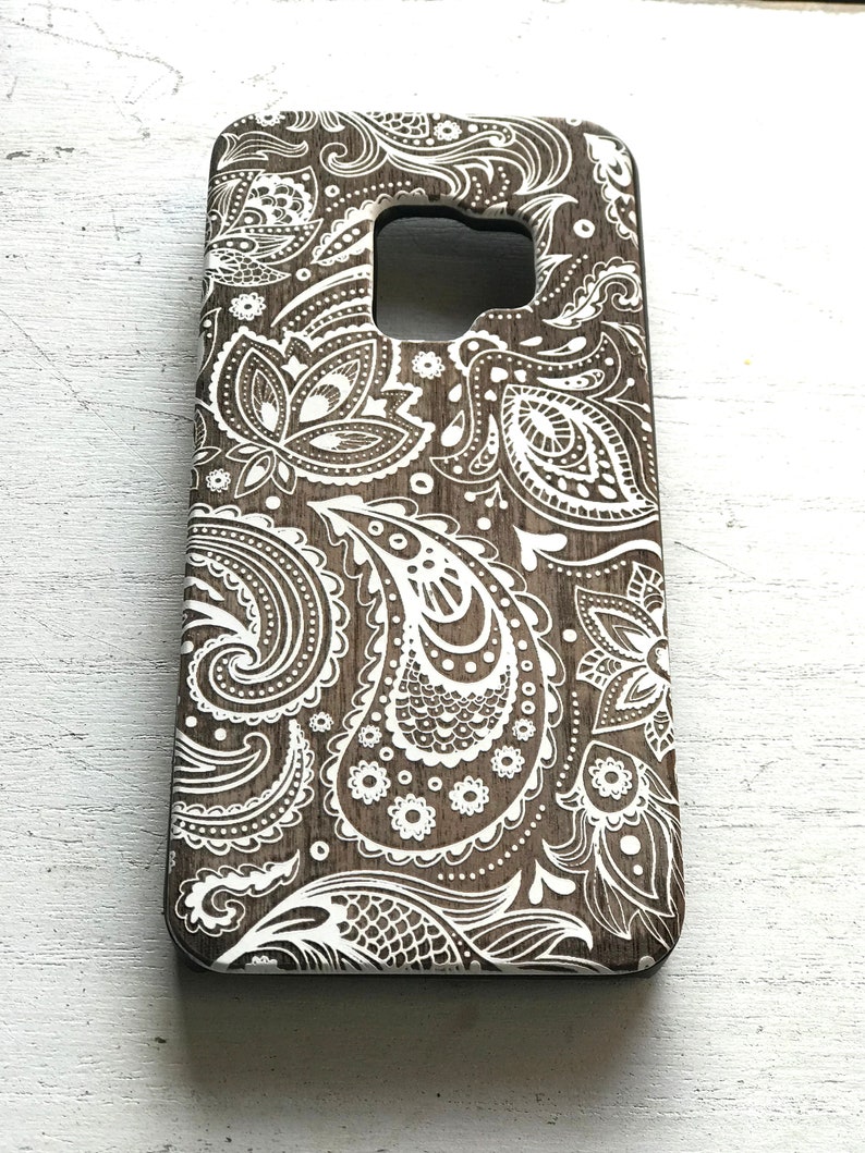 May include: A brown phone case with a white paisley pattern.