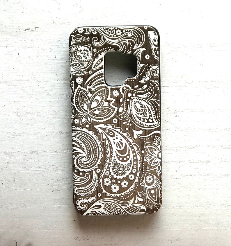 May include: A brown phone case with a white paisley pattern.