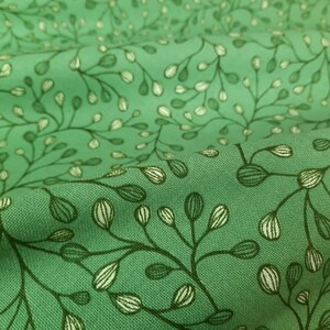 Op de afbeelding: Groene stof met een wit en groen bloemenpatroon. De stof heeft een subtiele textuur.