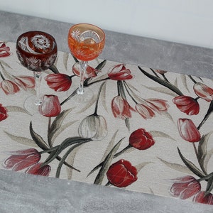 Könnte beinhalten: Ein beiger Tischläufer mit einem floralen Muster aus roten und weißen Tulpen. Zwei klare Glaskelche mit geschnittenen Glasdesigns befinden sich auf dem Läufer.