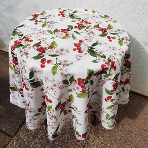 May include: White round tablecloth with a cherry blossom and cherry print. The tablecloth features red cherries and pink flowers on a white background.