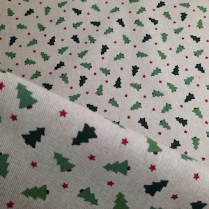 Op de afbeelding: Een beige stof met een herhalend patroon van groene kerstboompjes en rode sterren.