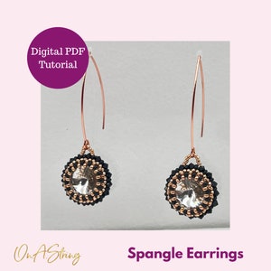 Könnte beinhalten: Ein Paar Hängeohrringe mit einem klaren Kristall, umgeben von schwarzen und goldenen Perlen. Die Ohrringe befinden sich auf einem weißen Hintergrund. Der Text "Spangle Earrings" befindet sich am unteren Rand des Bildes.