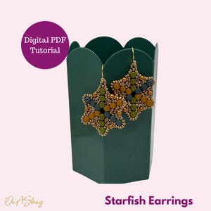 May include: Starfish earrings made with beads in shades of green, blue, and gold. The earrings are hanging from a green container with the text "Starfish Earrings" below.