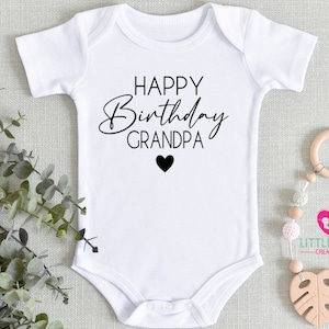May include: White baby onesie with black text that reads "Happy Birthday Grandpa" with a small black heart below the text.