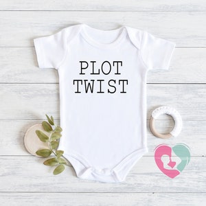 May include: White baby onesie with black text that reads "PLOT TWIST".