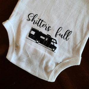 Op de afbeelding: Witte baby romper met een zwart silhouet van een camper en de tekst "Shitter's full".