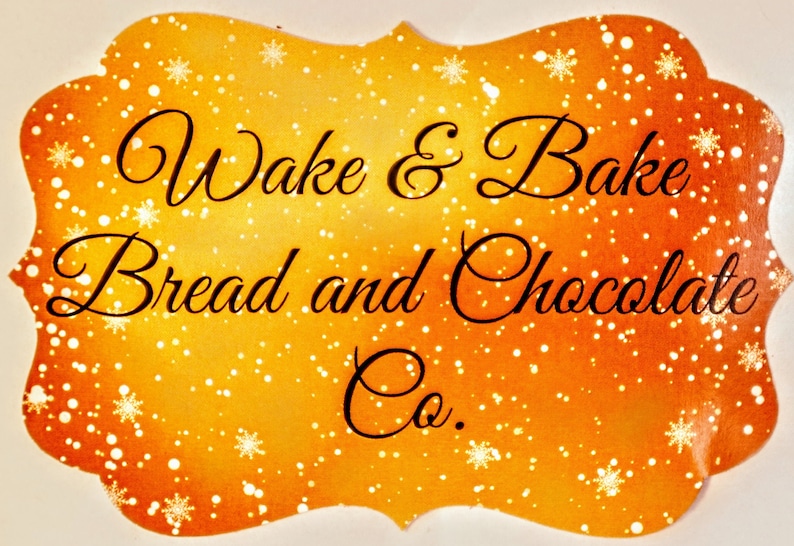 May include: A gold and orange sign with a white snowflake pattern. The sign reads "Wake & Bake Bread and Chocolate Co."