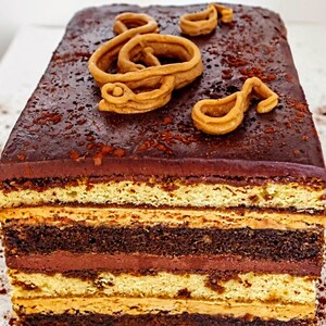 May include: A multi-layered chocolate cake with a chocolate ganache frosting and a decorative brown sugar treble clef on top.