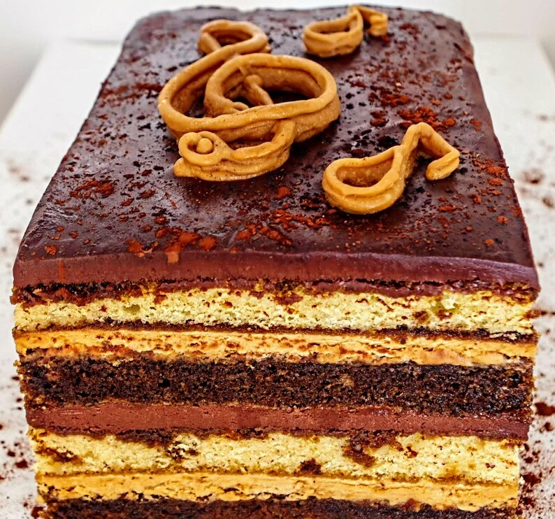 May include: A multi-layered chocolate cake with a chocolate ganache frosting and a decorative brown sugar treble clef on top.