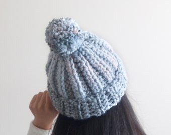 May include: A blue and pink knitted beanie with a fluffy pom pom on top.