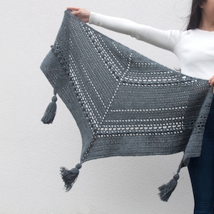 May include: A gray crocheted shawl with a geometric pattern and tassels.