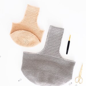 May include: Two crocheted bags, one beige and one gray, are laid out on a white surface.  A crochet hook and scissors are also pictured.