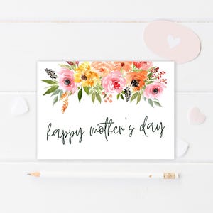 May include: A white card with a watercolor floral design in shades of pink, orange, and yellow. The text "happy mother's day" is written in black cursive.