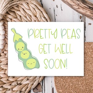 May include: A white greeting card with the text "Pretty Peas Get Well Soon!" in green script. The card features a cartoon illustration of a pea pod with three smiling peas. The card is on a woven surface.