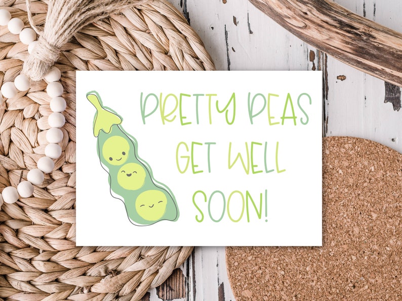 May include: A white greeting card with the text "Pretty Peas Get Well Soon!" in green script. The card features a cartoon illustration of a pea pod with three smiling peas. The card is on a woven surface.