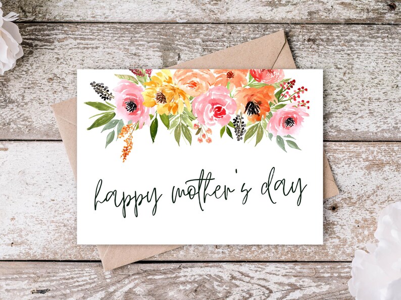 May include: A white card with a watercolor floral design in shades of pink, orange, and yellow. The text "happy mother's day" is written in black cursive.